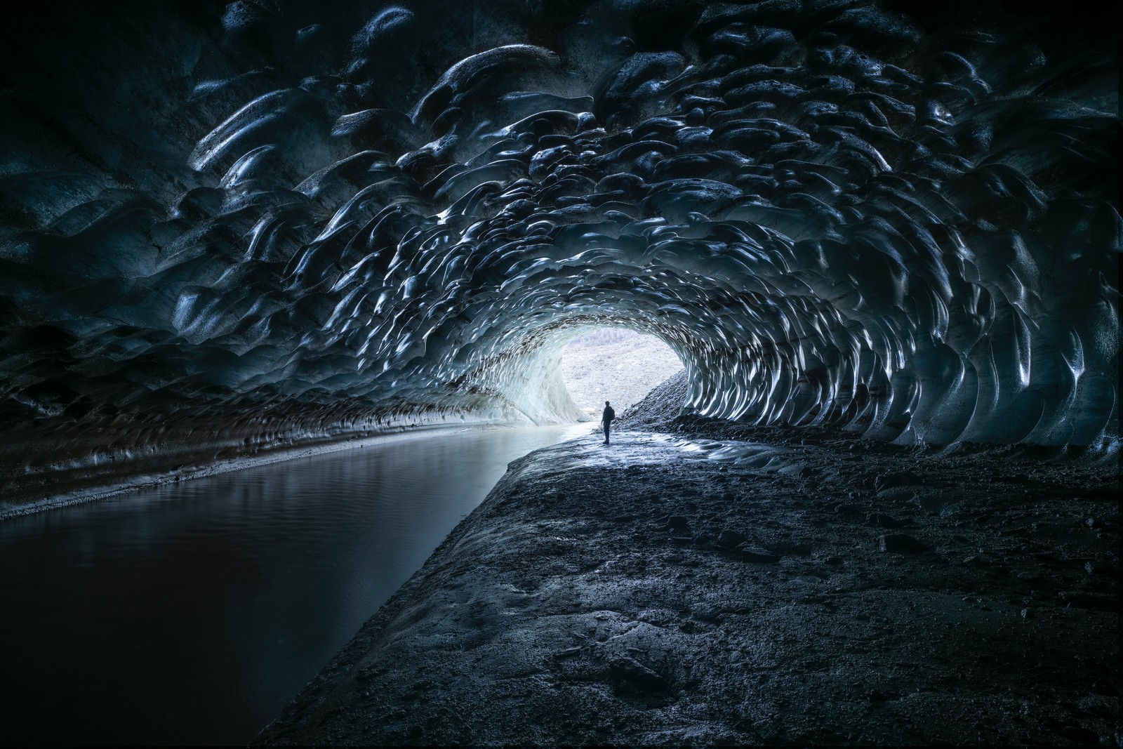 Ein mann steht in einer höhle mit einem gewässer (atmosphäre, wasserressourcen, wasser, fahrbahnoberfläche, asphalt)