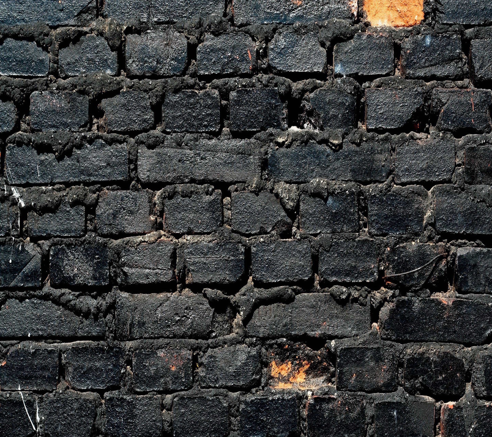 Un primer plano de un hidrante en una pared de ladrillo (negro, ladrillo, pared)