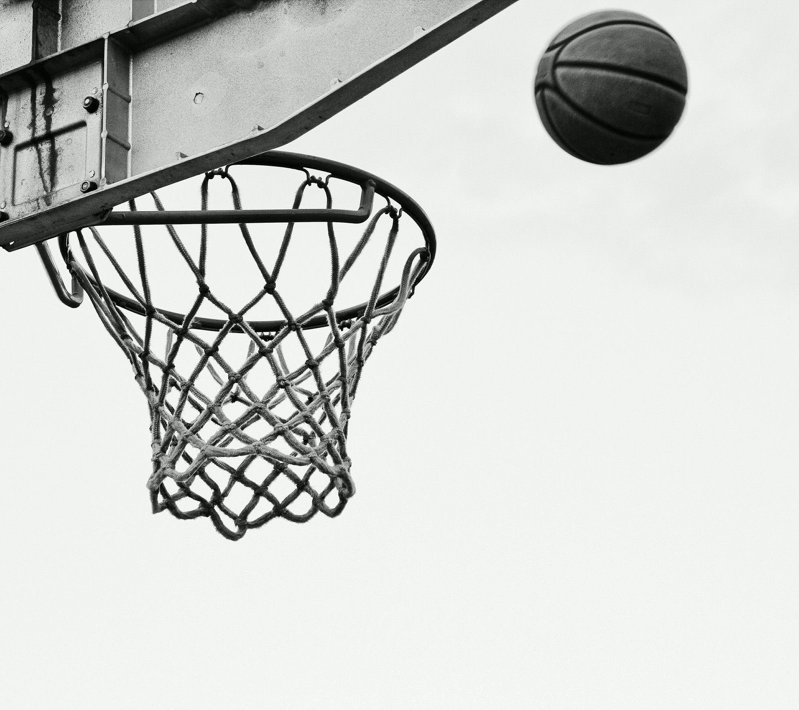 Imagen borrosa de un balón de baloncesto atravesando el aro con una pelota en el aire (baloncesto, blanco y negro, diversión, deporte)