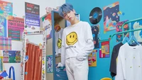 Soobin from Tomorrow X Together poses in a vibrant, colorful room filled with playful decor and retro elements, embodying a youthful and artistic spirit.