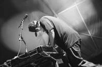 Musician performing passionately on stage with a plucked string instrument in a dynamic black and white setting.