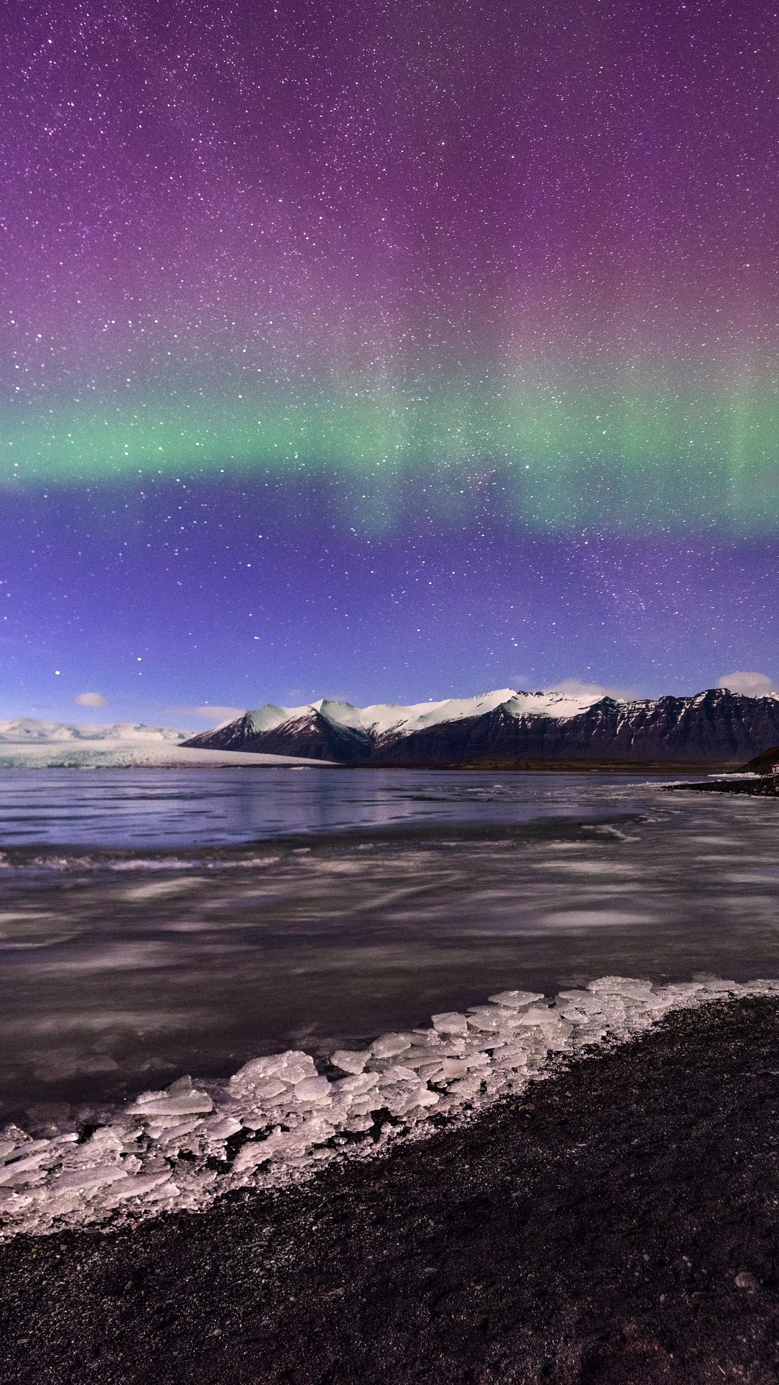 Lumières aurorales violettes et vertes au-dessus d'un plan d'eau avec des montagnes en arrière-plan (aurore, glacier, lumière, eau, paysage naturel)