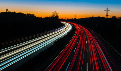 Rodovia Noturna Dinâmica: Luzes Fluindo Contra um Céu Crepuscular