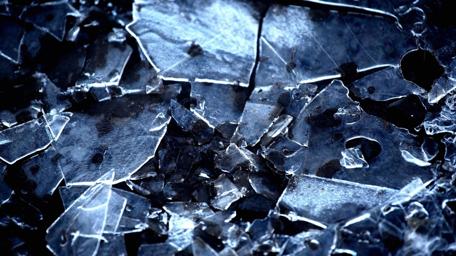 Nahaufnahme eines zerbrochenen fensters auf schwarzem hintergrund (wasser, blau, eis, kristall, metall)