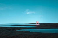 Surrealistische türkisfarbene Landschaft mit einem rosa Stuhl unter klarem Himmel