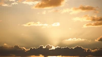 Atardecer dorado con nubes cúmulo y resplandor