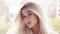 Ariana Grande mit langen blonden Haaren und einem natürlichen Schönheitslook, der ihren makellosen Teint und eleganten Stil zeigt.