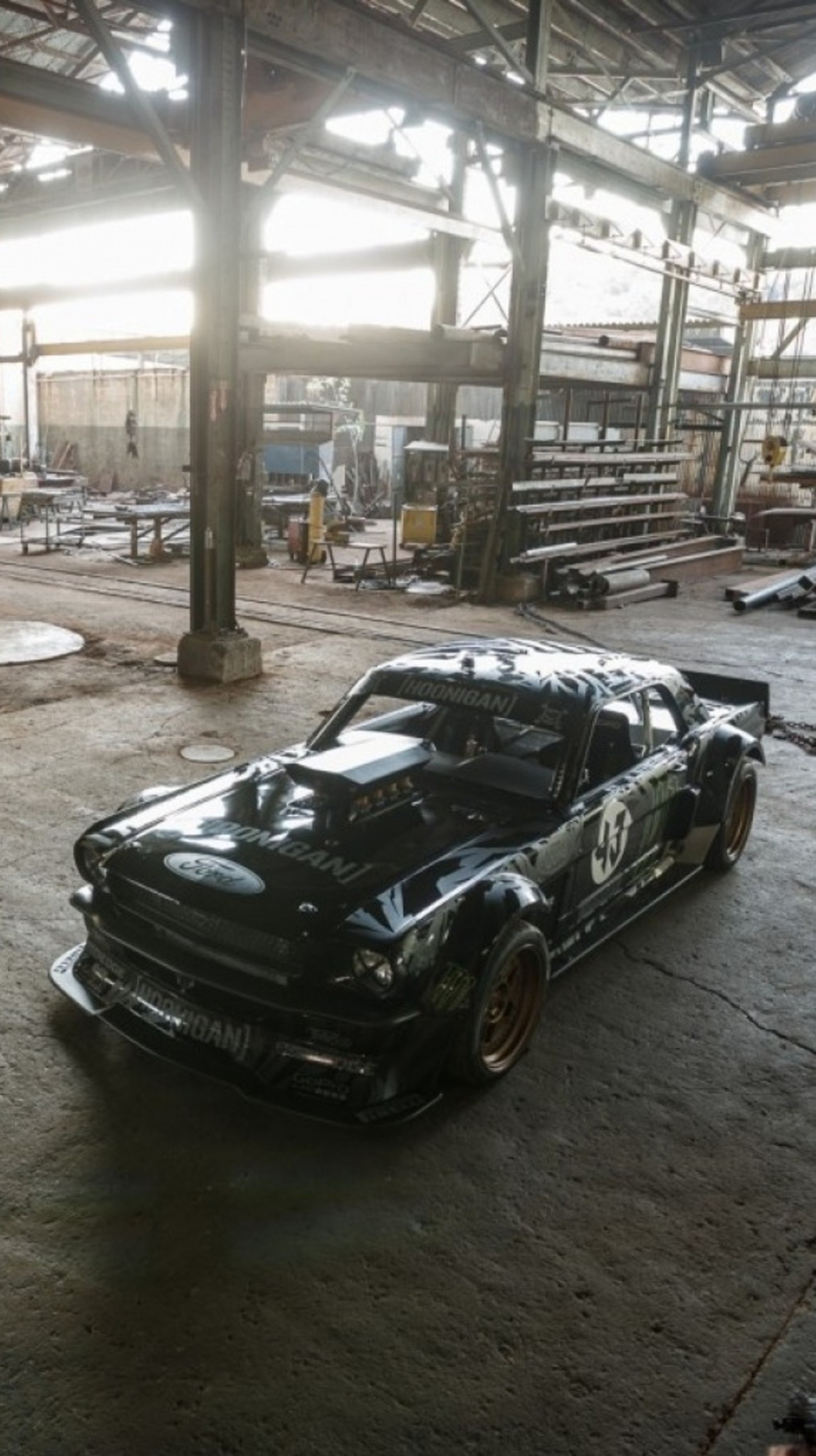 Arafed black car in a warehouse with a lot of junk (black, car, muscle, mustang)