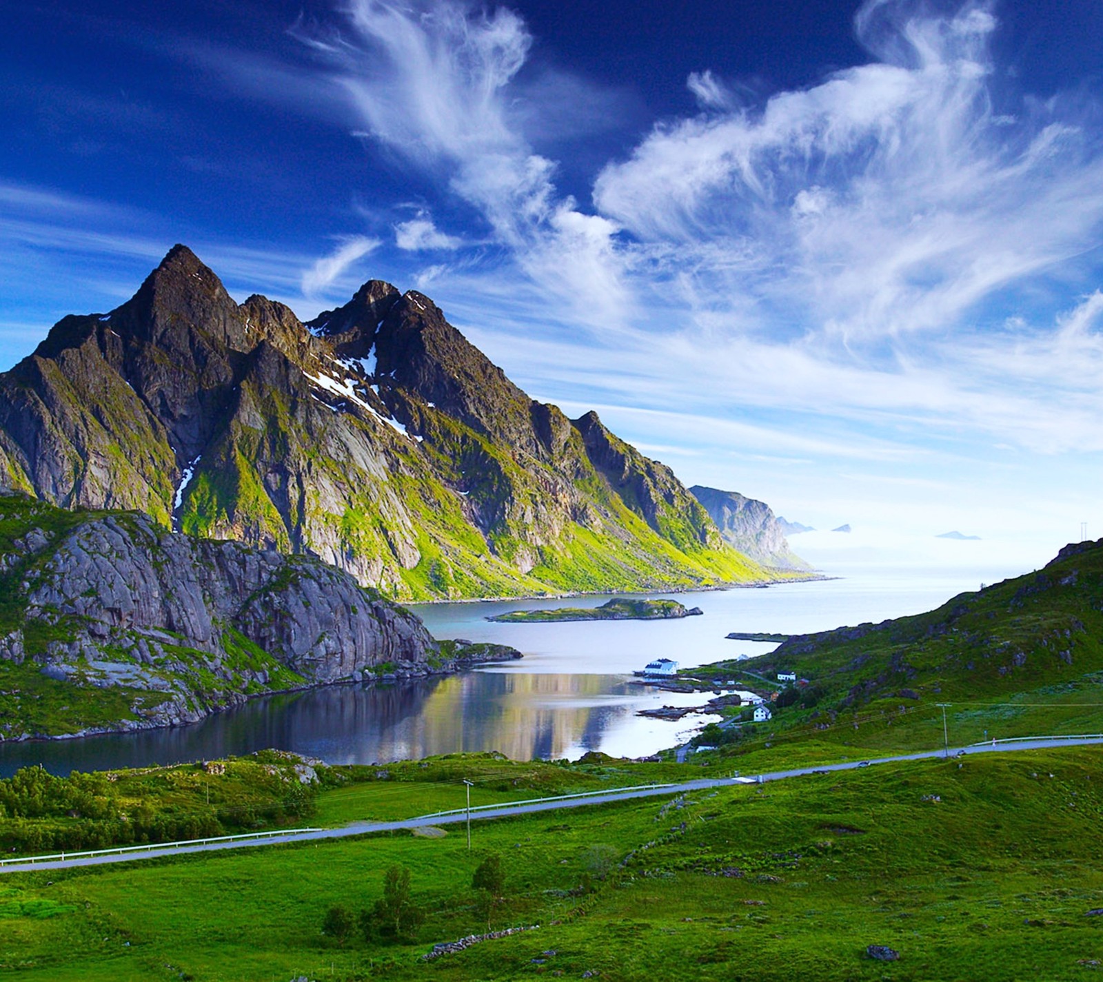 Une chaîne de montagnes avec une route qui la traverse (bleu, herbe, vert, lac, paysage)