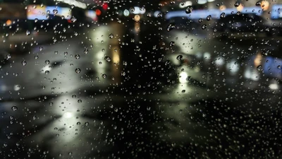 Gotas de lluvia en una ventana con reflejos de luces de la ciudad