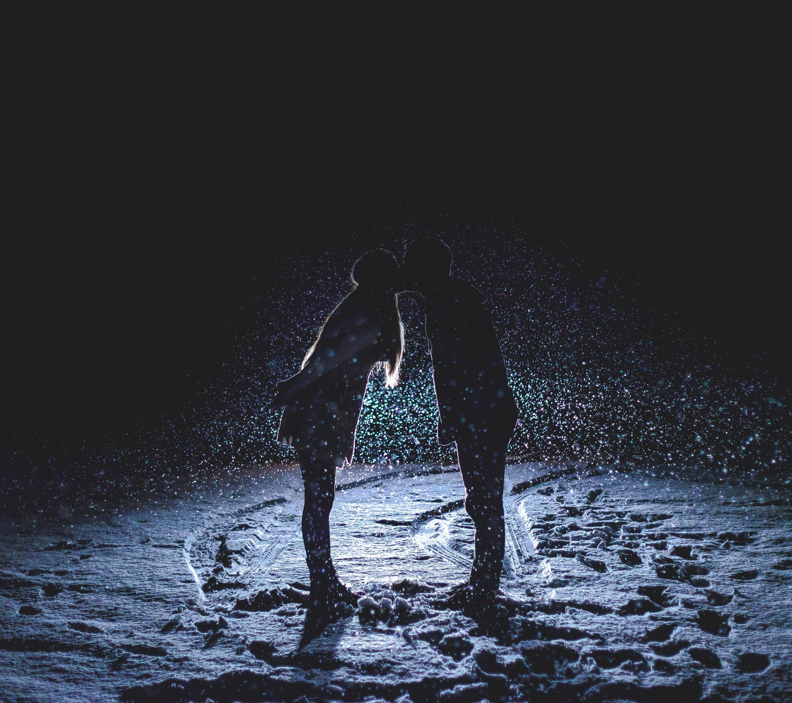 There are two people standing in the snow at night (black, dark, kiss, kissing, love)