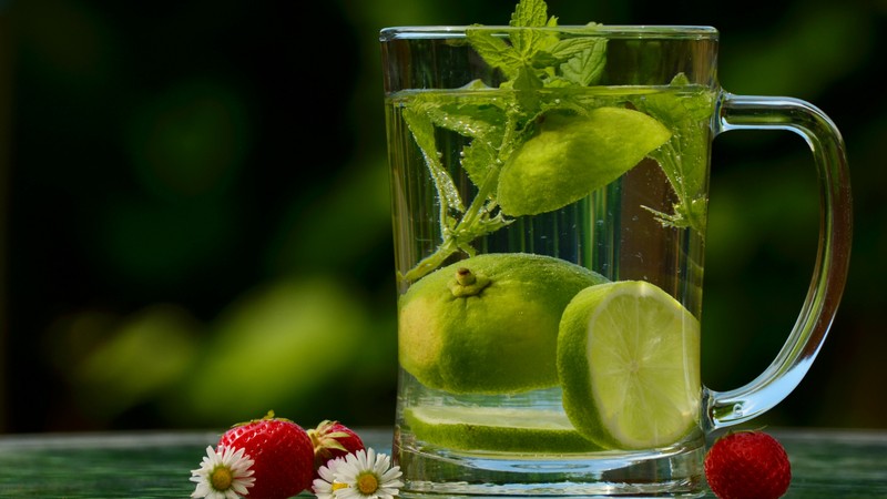 На столе стоит стакан воды с лаймом и клубникой (мохито, лимон, лайм, lime, вода)