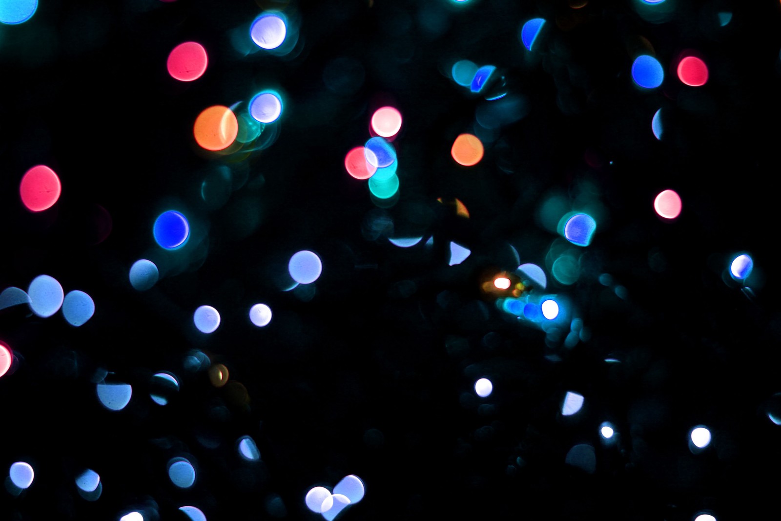 Des lumières colorées brillent intensément sur un fond noir (bokeh, lumière, éclairage, espace, obscurité)