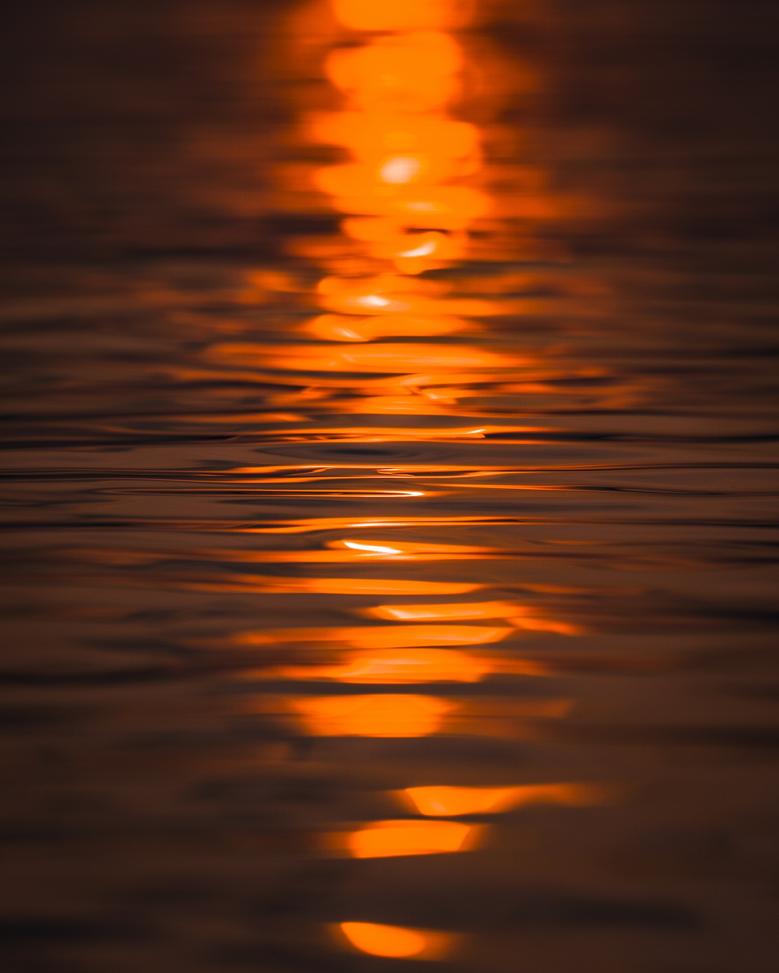 Une image floue d'un coucher de soleil se reflétant dans l'eau (réflexion, eau, orange, calme, crépuscule)