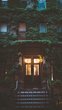 Illuminated Entrance of a Green-Embraced House at Dusk