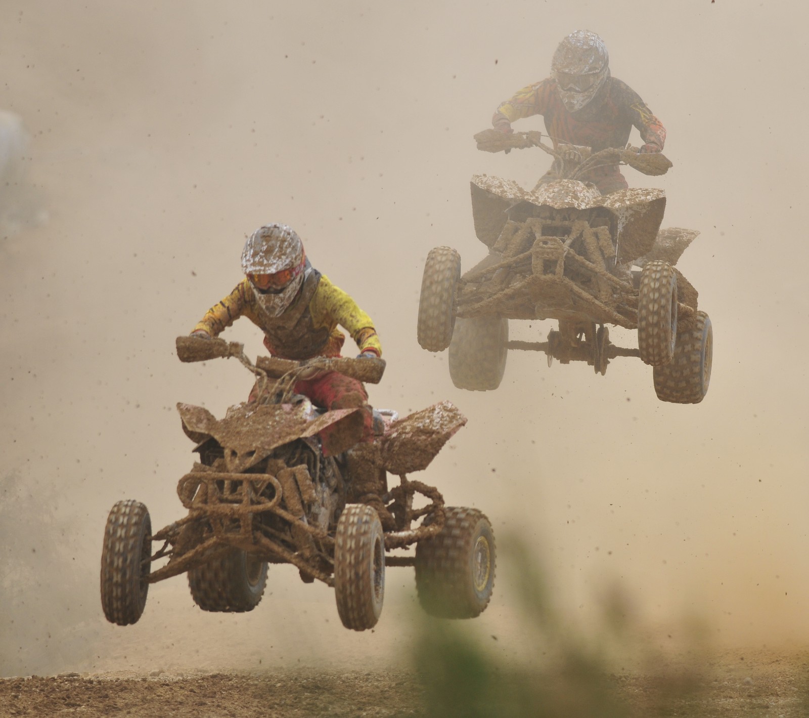 Deux personnes sur des quads dans la terre avec une moto tout terrain (vélos, saleté, courses, piste)