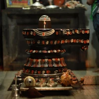 A traditional Shiva Lingam with intricate designs, surrounded by offerings and a decorative backdrop.