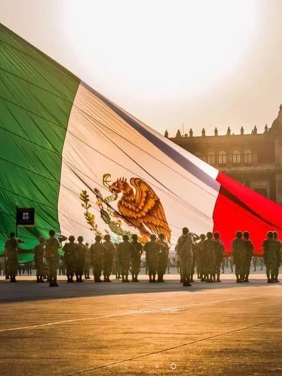 Soldados mexicanos saudando sob a enorme bandeira do México