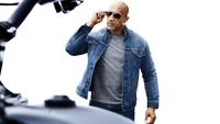 Dwayne Johnson in a denim jacket and sunglasses, exuding confidence and style against a clean background.