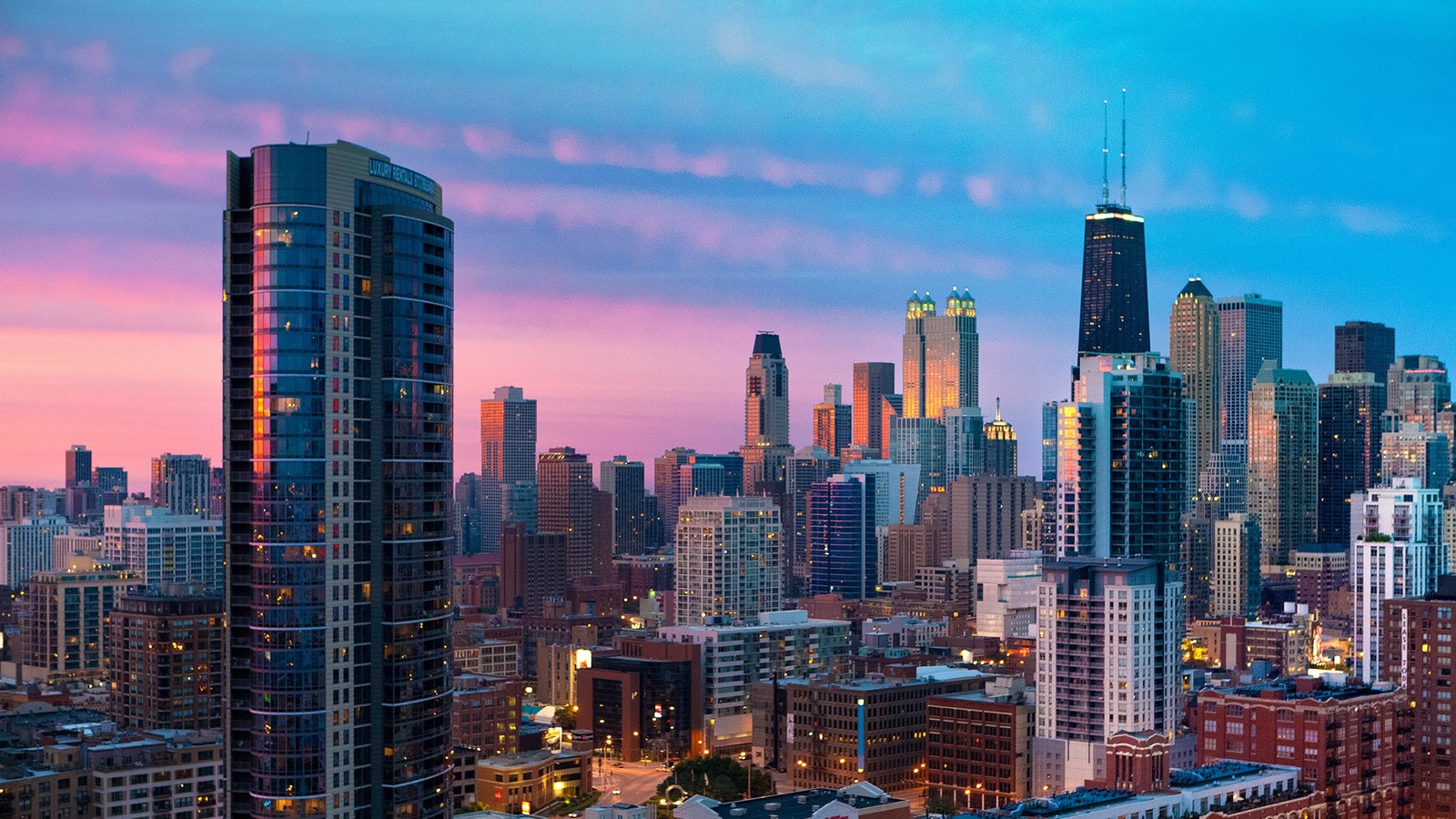 Vista aérea del horizonte de una ciudad al atardecer con un cielo rosa (ciudad, paisaje urbano, área urbana, panorama, rascacielos)