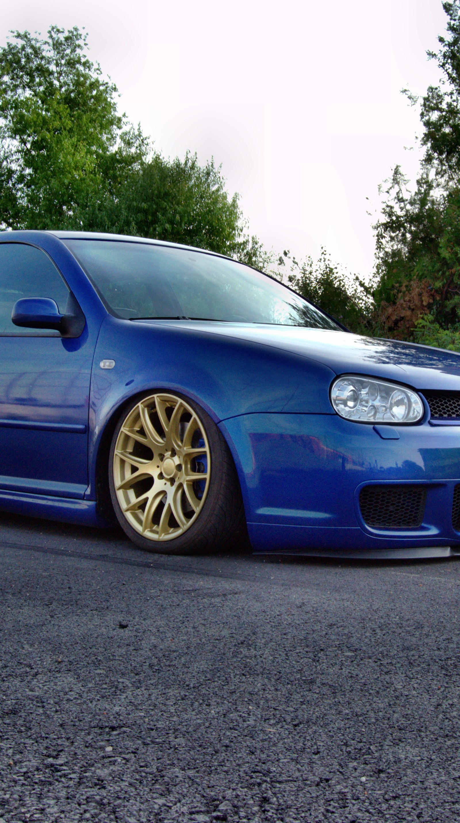 Arafed blue car parked on the side of the road with trees in the background (3sdm, airride, golf, mk4, vw)