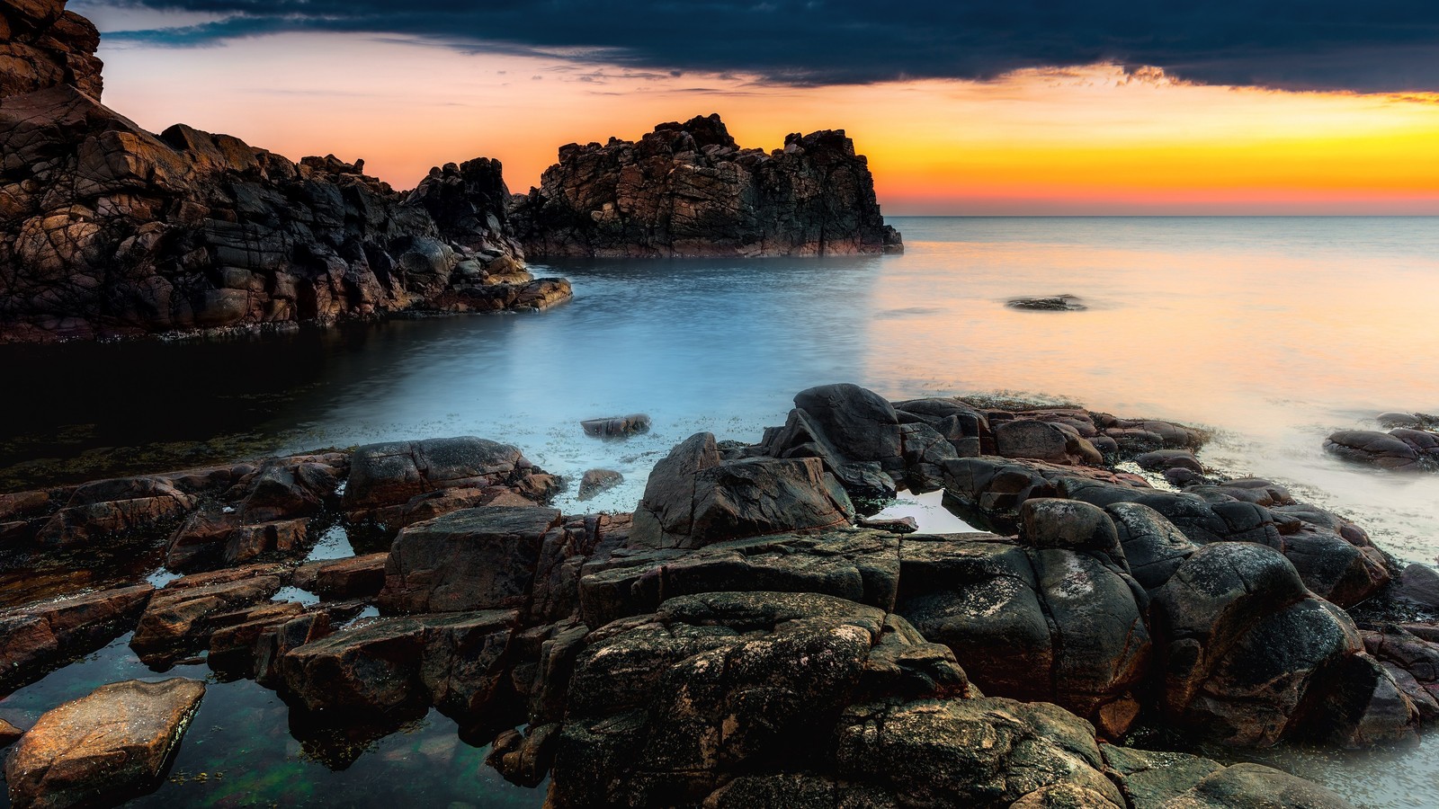 Une vue d'une plage rocheuse avec un coucher de soleil en arrière-plan (paysage marin, mer, paysage, nature)