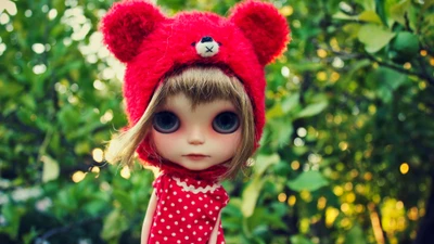 Whimsical Blythe Doll in a Red Bear Hat Among Greenery