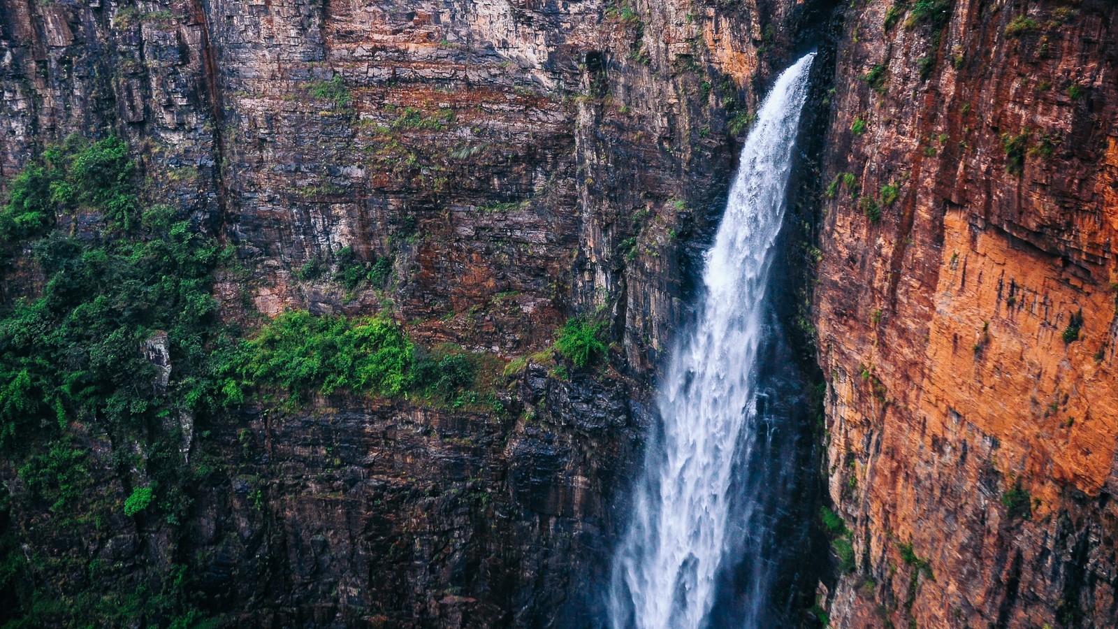 A close up of a waterfall in a canyon with a cliff in the background (waterfall, body of water, water resources, nature, water)