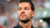 A focused soccer player with a prominent beard and expressive features, representing Germany in a dynamic sports setting.