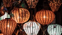 Colorful paper lanterns illuminating a dark space, showcasing intricate designs and warm light.