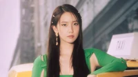 Yoona de Girls' Generation con un elegante atuendo verde, irradiando confianza y elegancia contra un vibrante fondo urbano.