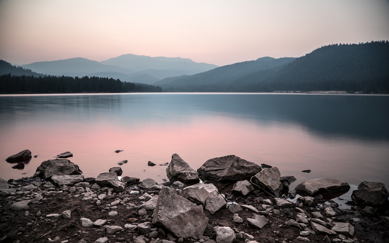 Una vista de un lago con rocas y una montaña al fondo (naturaleza, montaña, paisaje natural, desierto, paisaje)