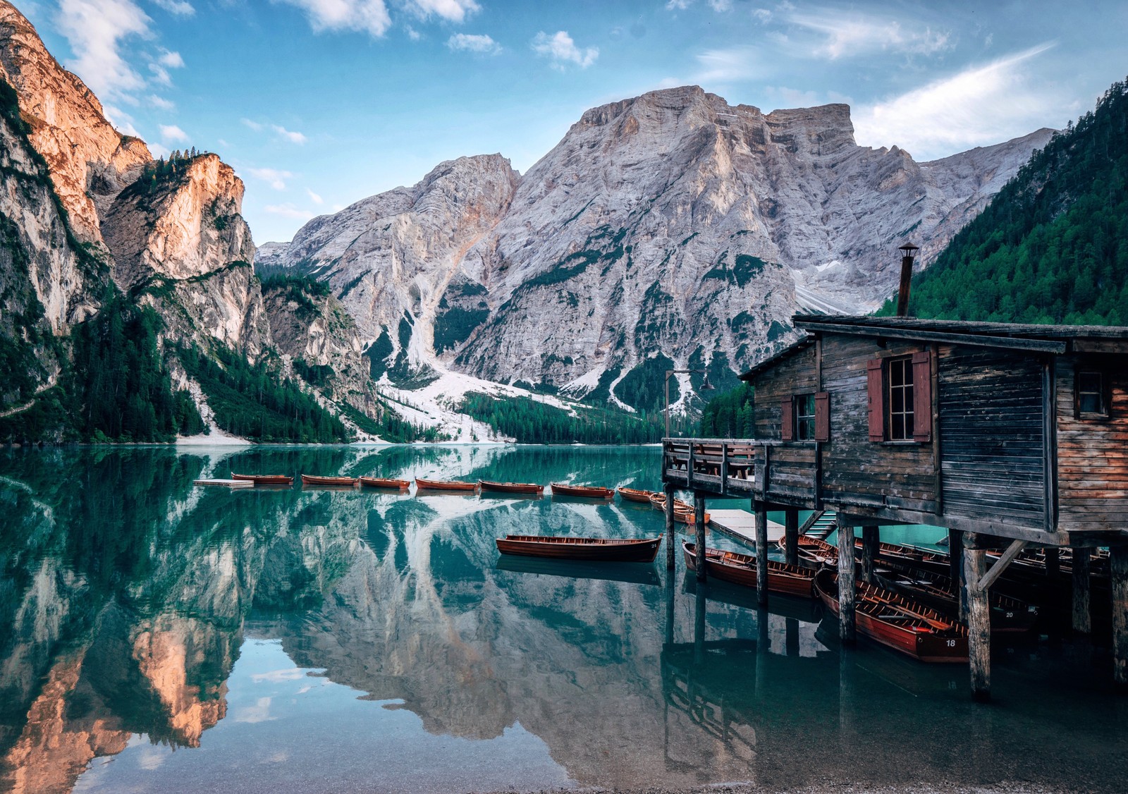 Uma vista de um lago com barcos ancorados nele e montanhas ao fundo (lake braies, itália, casa de madeira, barcos, montanhas)