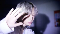 Choi Beomgyu de TXT dans une pose dramatique, illuminé par une lumière douce.