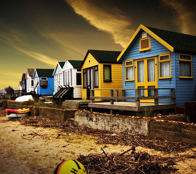 Há muitas casas na praia com uma prancha de surf na areia (praia, casas)