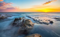 Pôr do sol tranquilo sobre a costa rochosa com ondas do oceano