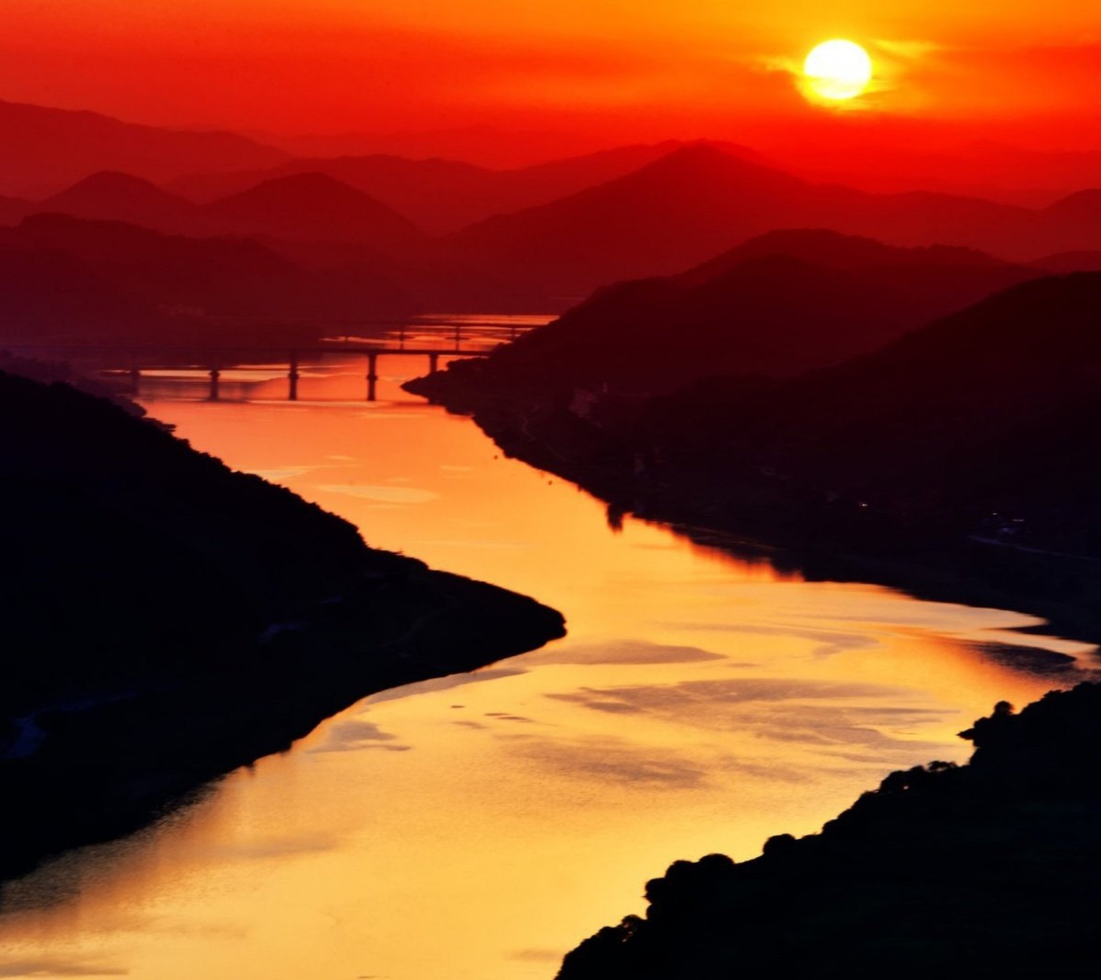 Vue aérienne d'une rivière avec un pont au loin. (nature, flueve, coucher de soleil)