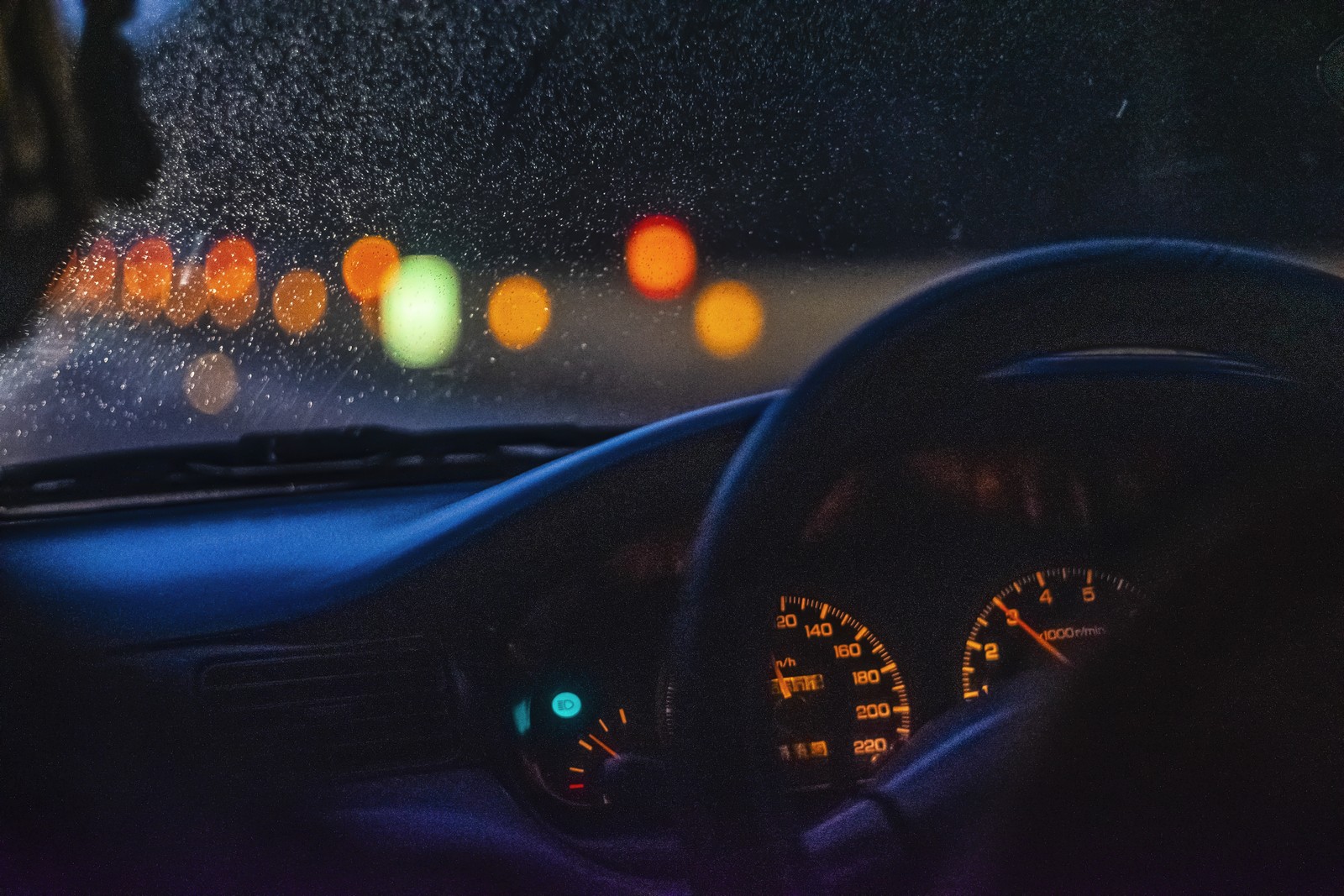 Eine draufsicht auf ein armaturenbrett mit eingeschaltetem armaturenlicht (mustang, regen, regentropfen, bokeh, tachometer)