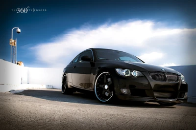 Sleek black BMW 3 Series with custom rims captured against a clear blue sky.