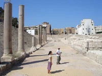 Ruinen einer antiken römischen archäologischen Stätte mit Touristen, die historische Säulen erkunden.