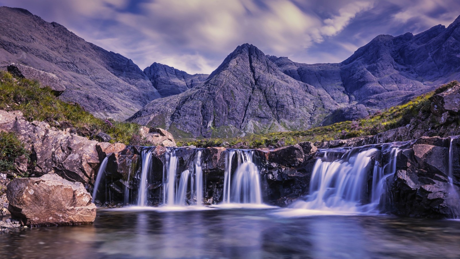 Una cascada en las montañas con un cielo nublado encima (cascada, montaña, cuerpo de agua, naturaleza, agua)