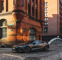 Audi RS e-tron GT estacionado frente a un edificio histórico de ladrillo, mostrando lujo y rendimiento eléctrico moderno.