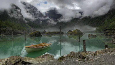 Lago sereno rodeado de montañas y niebla con un bote anclado cerca