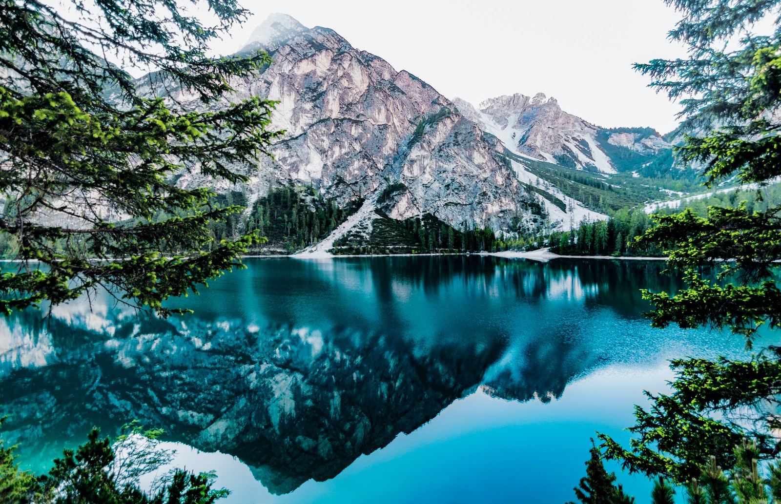 Um lago cercado por árvores e montanhas com uma montanha ao fundo (lago da montanha, reflexo, água azul, paisagem, cenário)