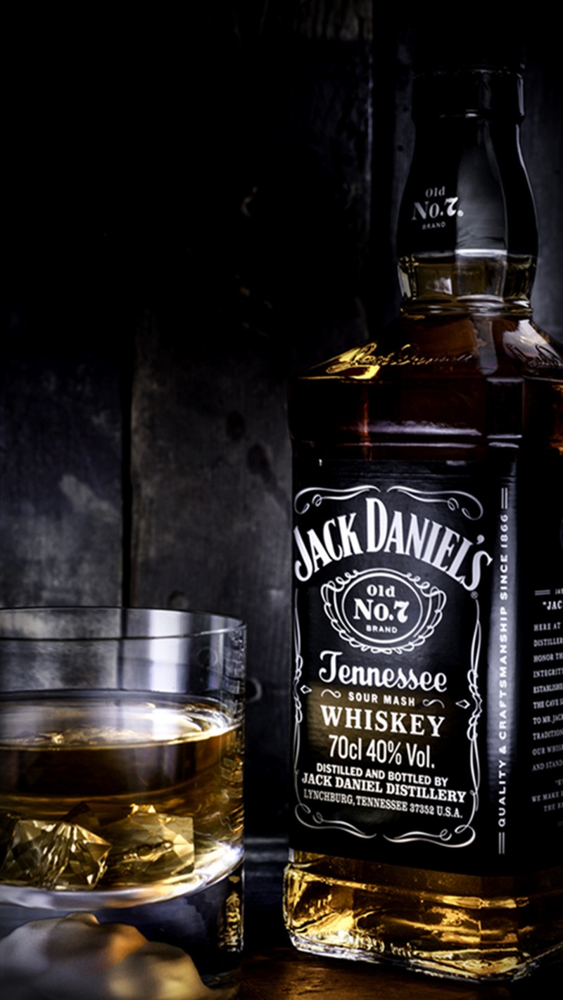 Рядом с бокалом виски стоит бутылка jack daniels (джек даниэльс, jack daniels, виски)