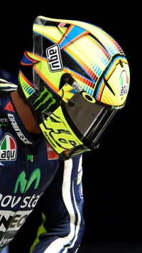 Valentino Rossi in his iconic AGV helmet, showcasing vibrant colors and sponsor logos.