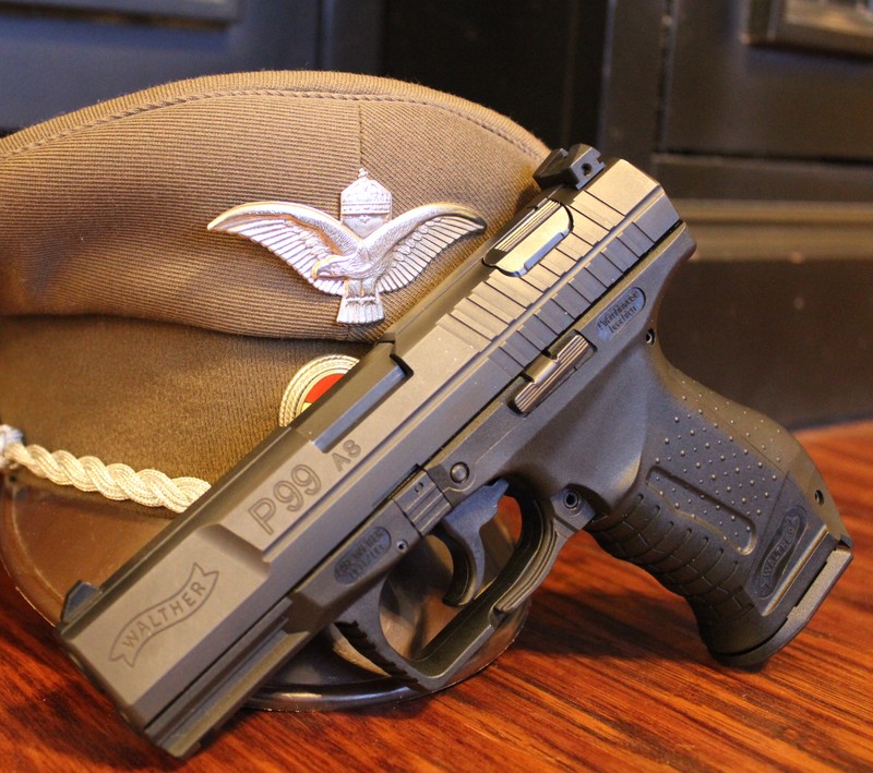 A close up of a gun and a hat on a table (bond, p99, walther)