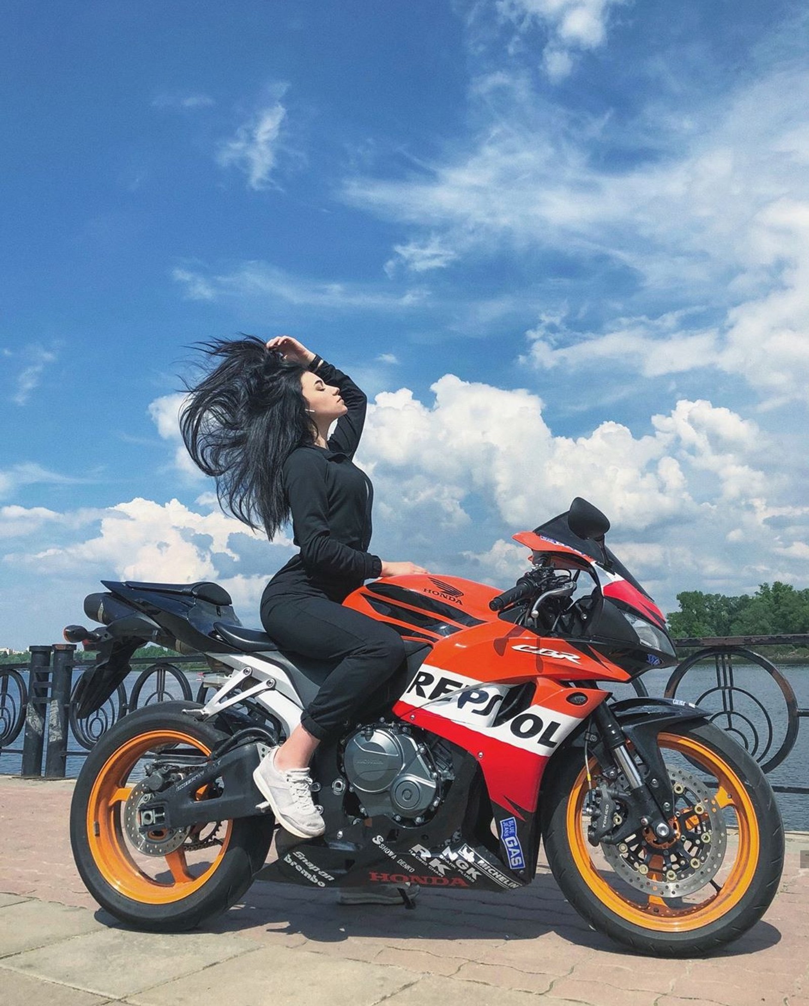 Una mujer sentada en una motocicleta con su cabello volando con el viento (bicicleta, niña, honda, modelo, moto)