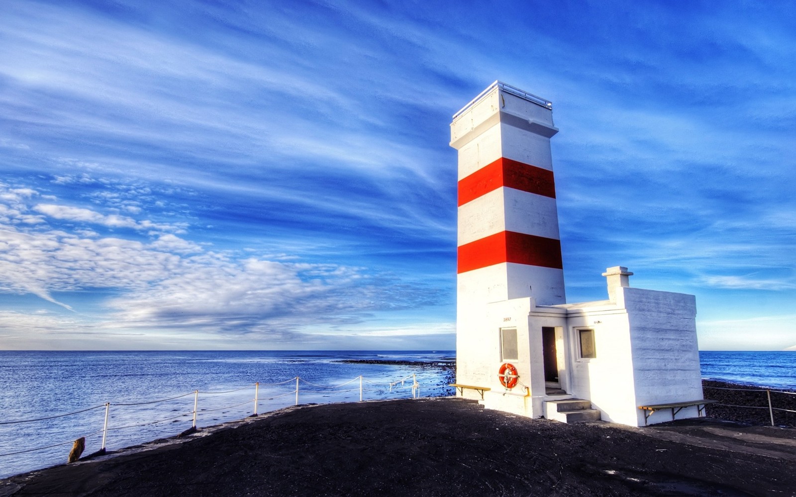 Farol em uma costa rochosa com céu azul (torre, farol, mar, oceano, nuvem)