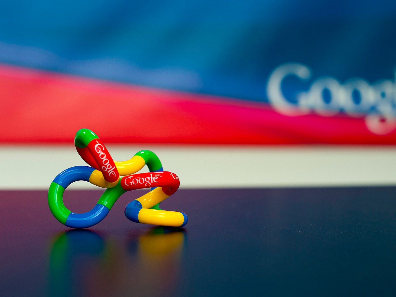 Hay un juguete de bicicleta con el logo de google en él (google, azul, rojo, cielo, fotografía macro)